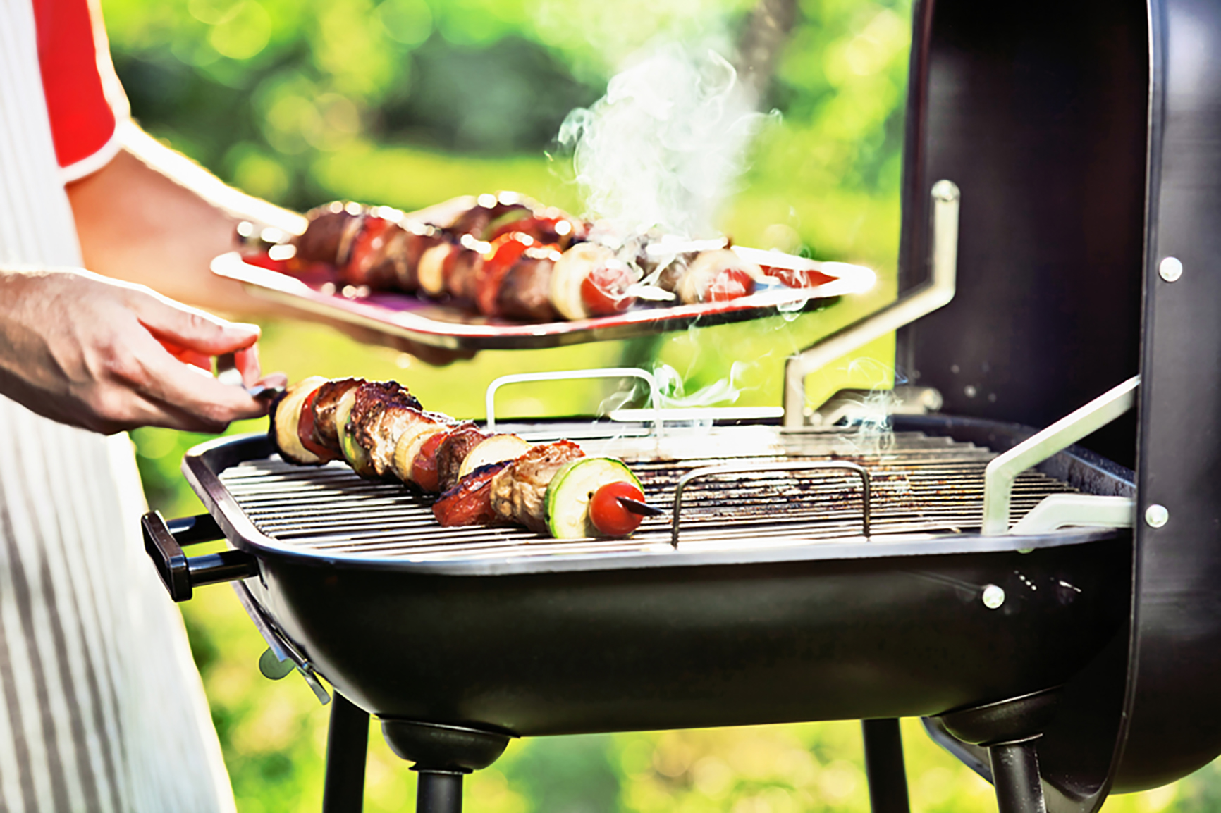 small barbecue grill with some grilled meat on sticks.